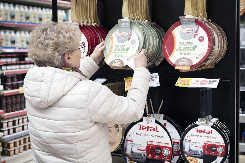 A woman chooses a non-stick frying pan in a Super U supermarket.