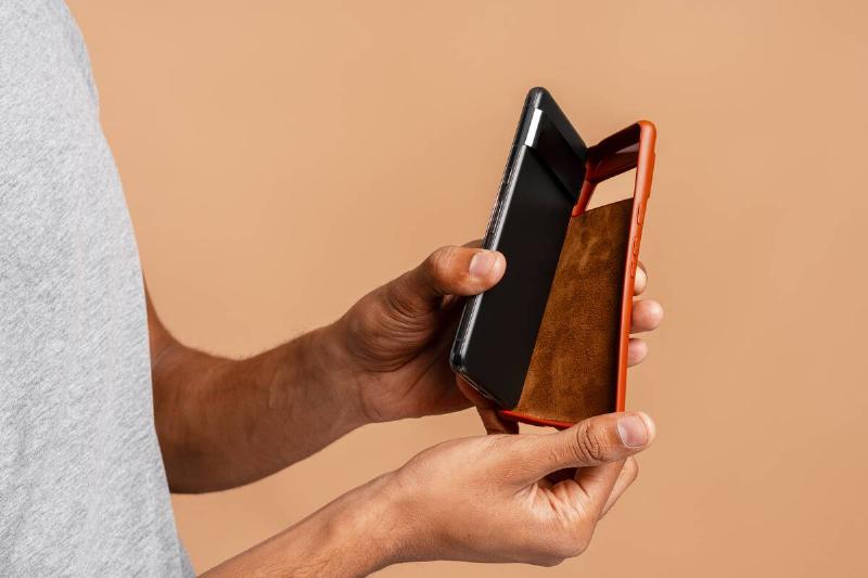 A ahnd taking a protective brown case off of a smartphone.
