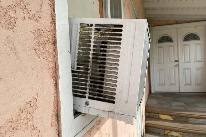 An air conditioner unit in the window of a house. 