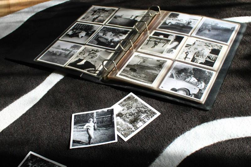 Photo album open on a blanket, with three loose photos strewn nearby