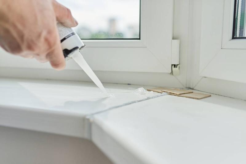Sealing up gaps near a window with caulk. 