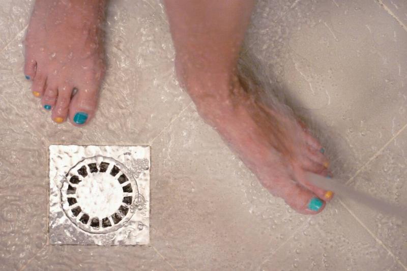 Unidentified individual standing near the drain of a shower