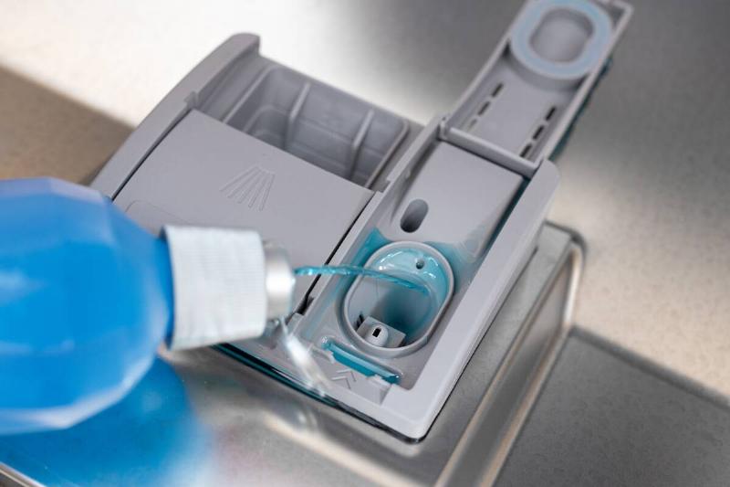 Pouring detergent in dishwasher. 