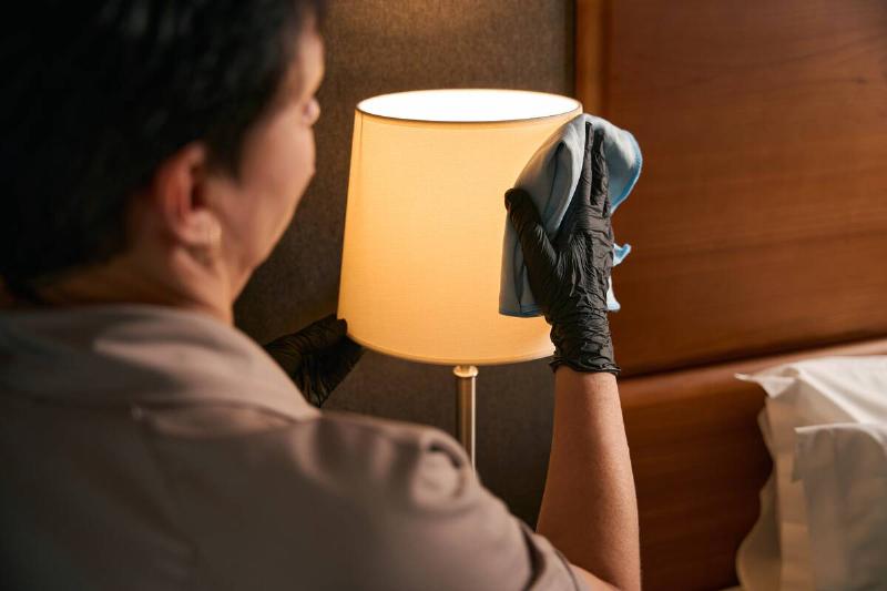 Woman cleaning bedside lamp