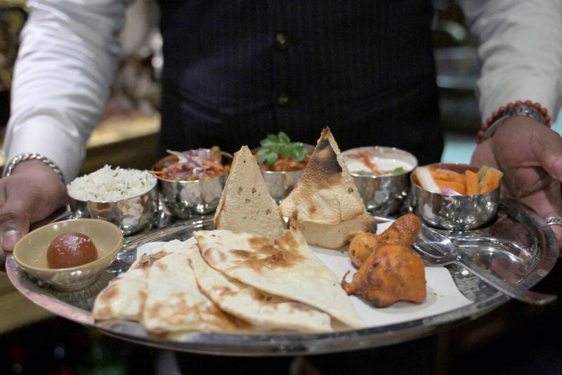 Waiter carrying an array of Indian food on a silver tray