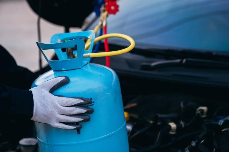 Person holding blue propane tank. 