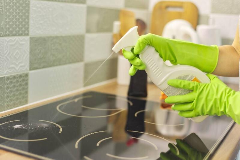 A person spraying cleaner on a stove. 
