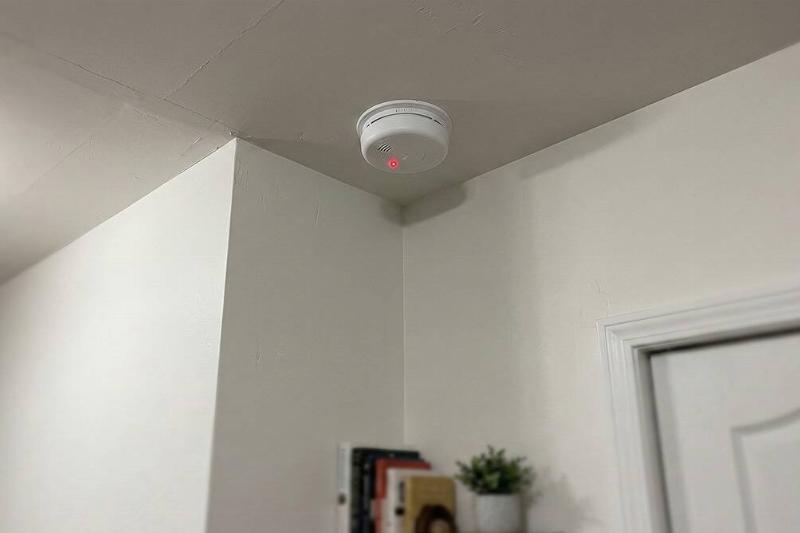A smoke detector in the corner of a room. 