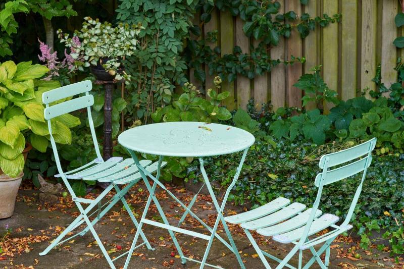 Metal patio furniture near a backyard fence. 
