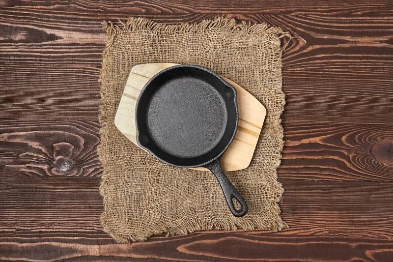 A cast iron skillet on a cutting board on a wooden table. 