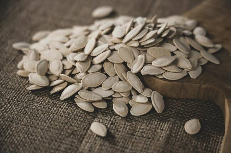 Close-up of pumpkin seeds spilling off a wooden cutting board