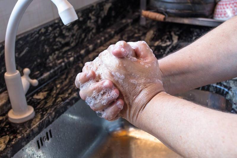Person washing hands at kitchen sink. 
