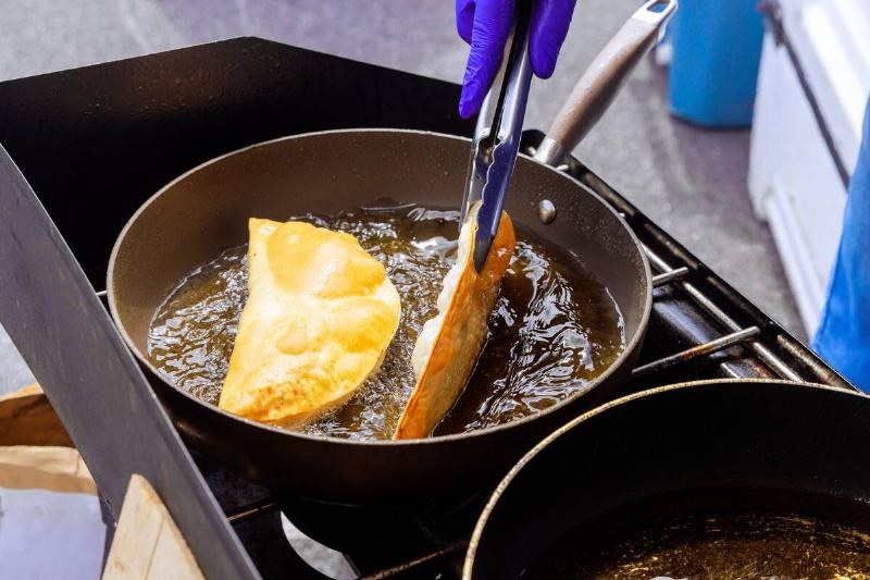Person frying food in oil on pan. 
