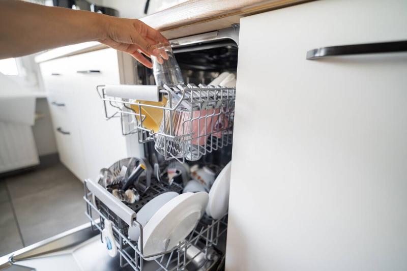 Hand taking dishes out of the dishwasher. 