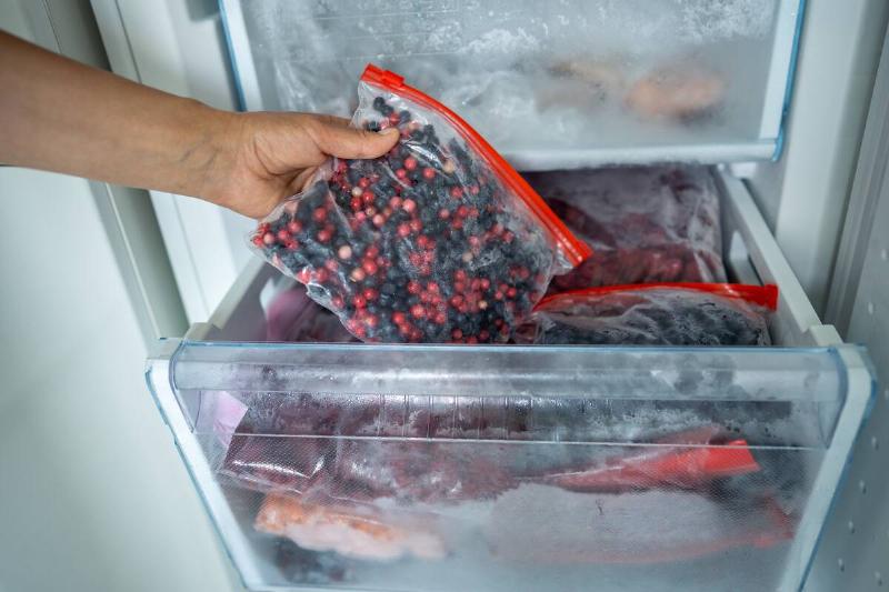Person pulling a bag of berries from a freezer