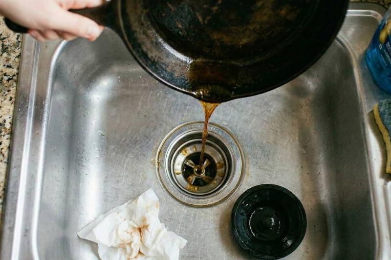 Bacon grease from a pan being poured down the drain.