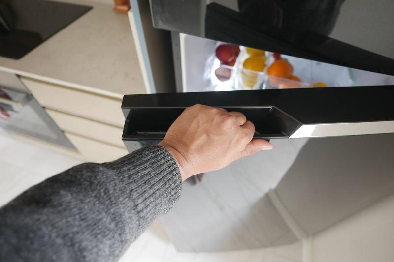 Person off-screen opening a fridge