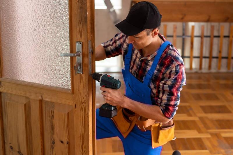 Man using drill on wooden door. 