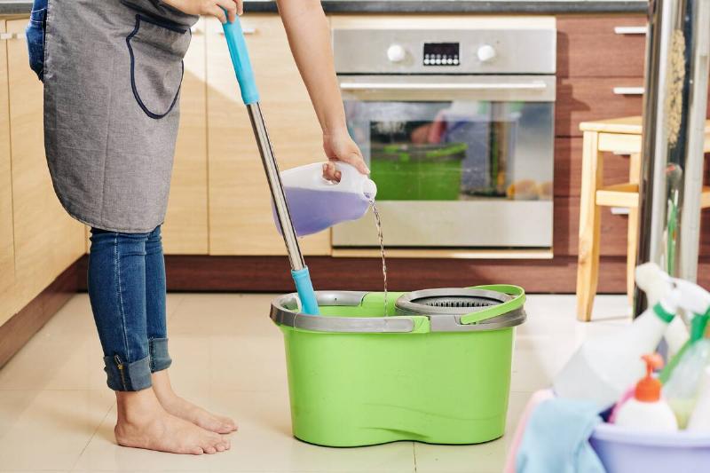 Woman pouring soap into mop bucket. 