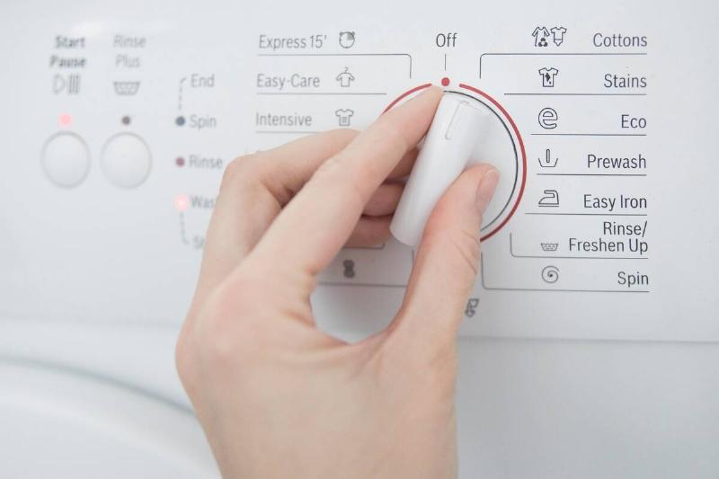 Hand selecting setting on washing machine. 