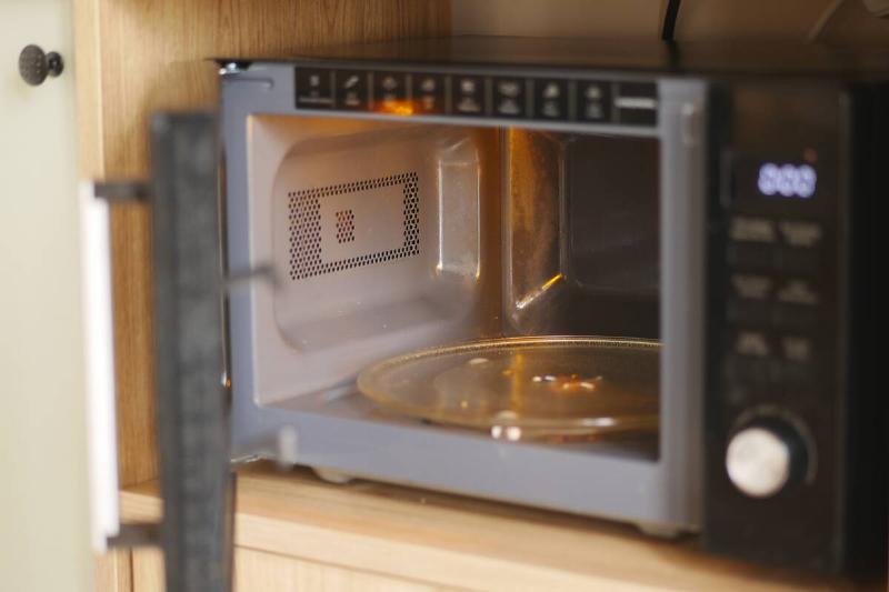A microwave oven sits on a kitchen counter with the door open.