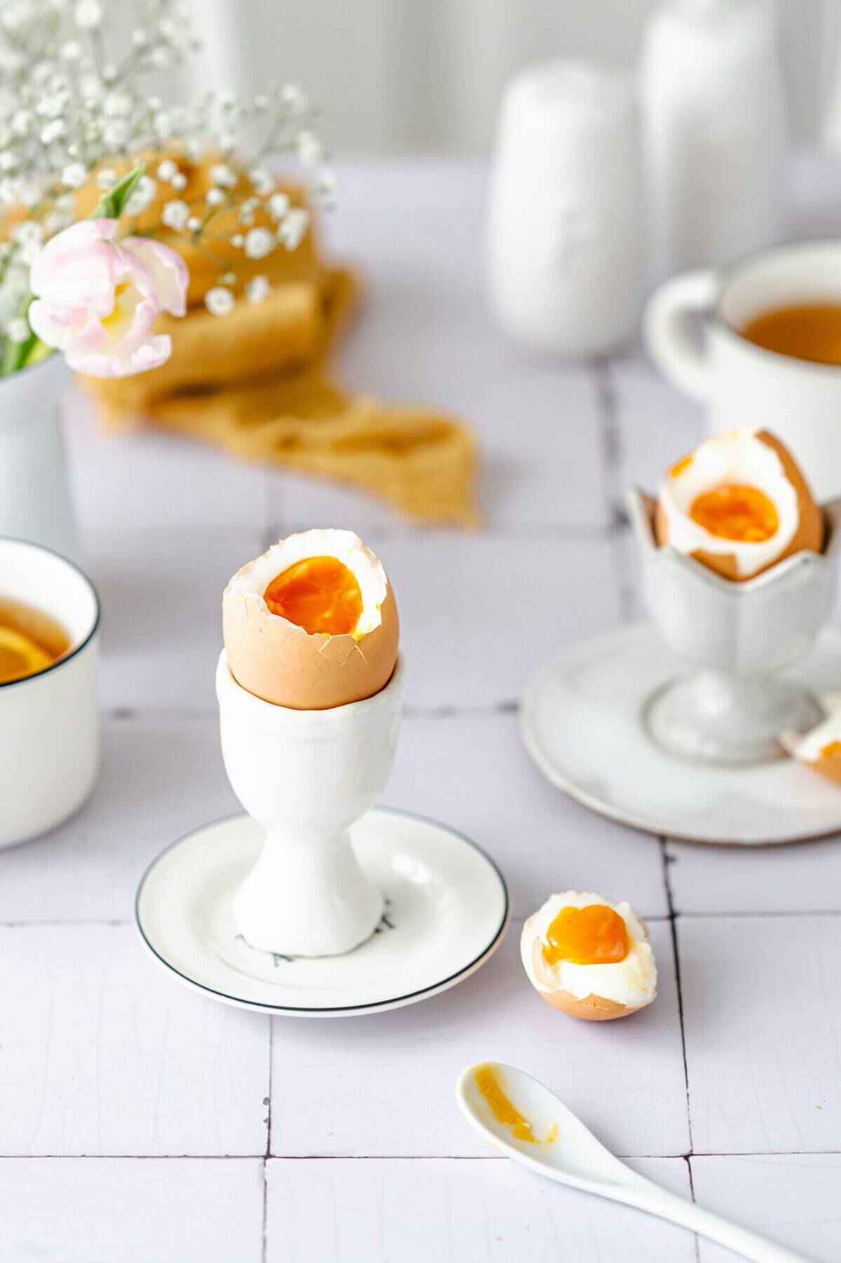 Two hard-boiled eggs in egg cups that are atop small plates
