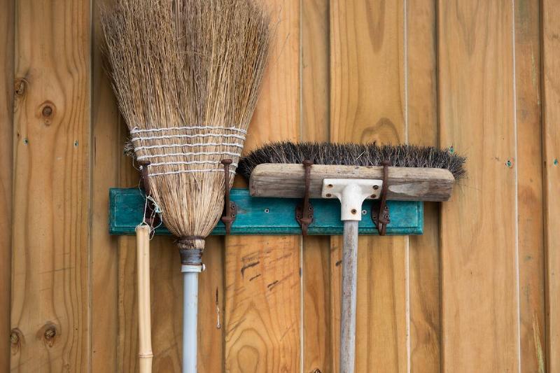 Two old brooms hanging on a wall. 