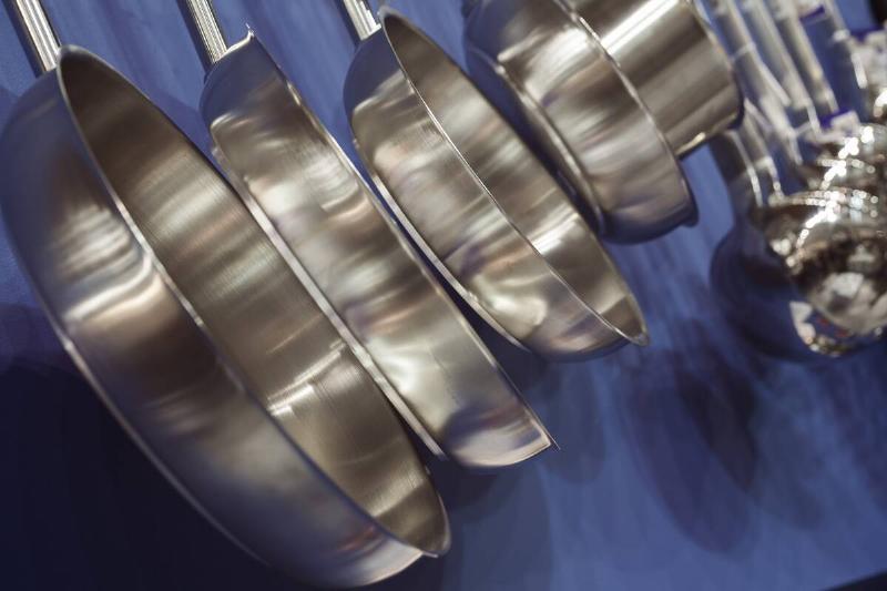 Stainless steel pans hanging near a blue wall. 