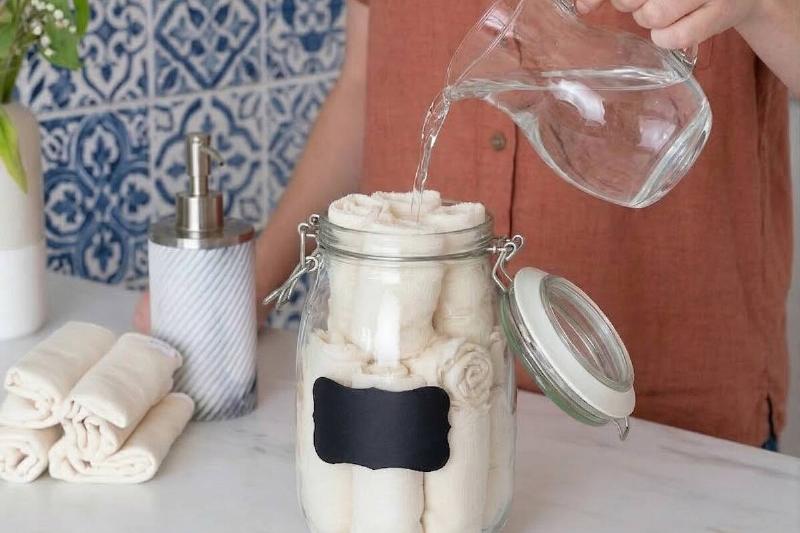 A person pouring the disinfectant liquid into the jar, over the cloths. 