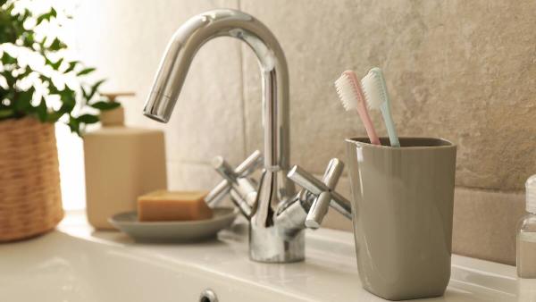 Toothbrushes in cup near sink. 