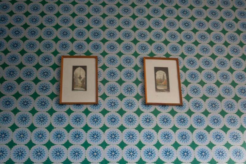 Two framed photos on a wallpapered wall