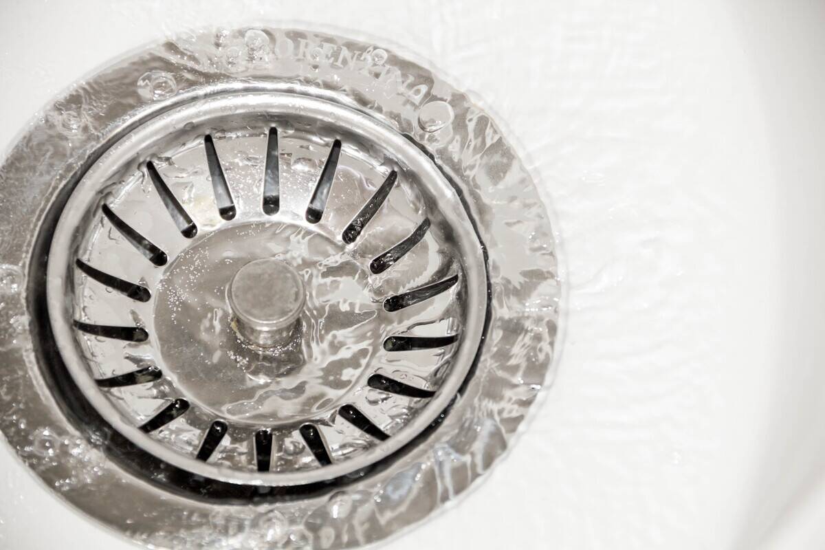 Close-up of a metal drain plug in the drain of a ceramic sink