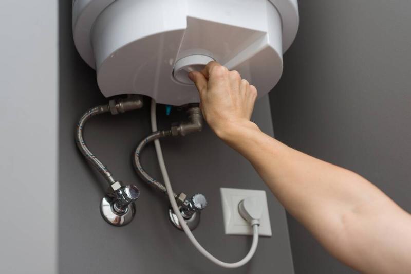 Woman hands setting temperature of water in heater electric boiler.