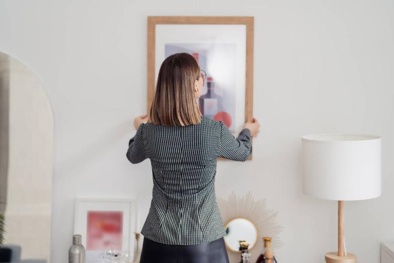 Back view of woman hanging a picture frame.