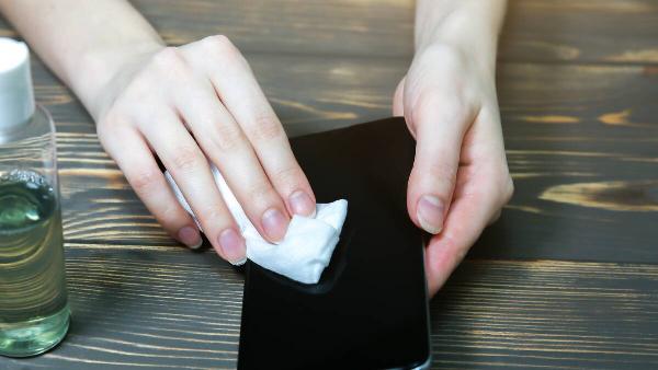 Cleaning a phone screen with an alcohol wipe. 