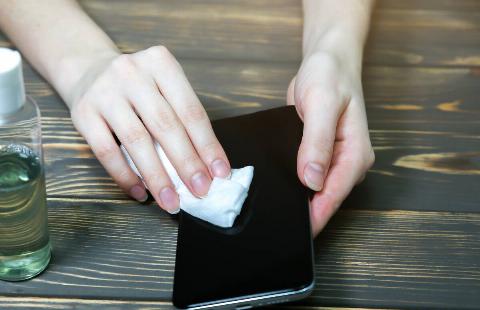 Cleaning a phone screen with an alcohol wipe. 