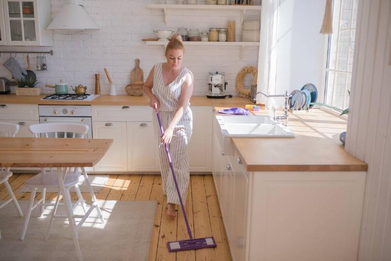 Woman mopping the floor in her kitchen. 