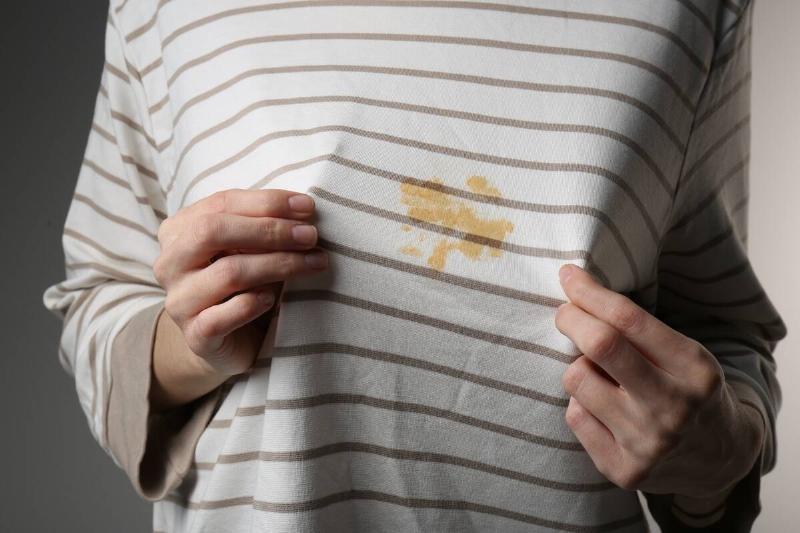 A person showing a grease stain on a shirt. 