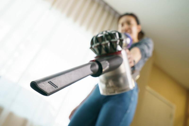 Woman holding vacuum with crevice attachment connected. 