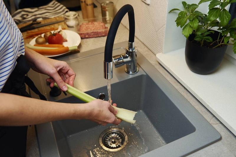 A person washing celery in their kitchen sink. 