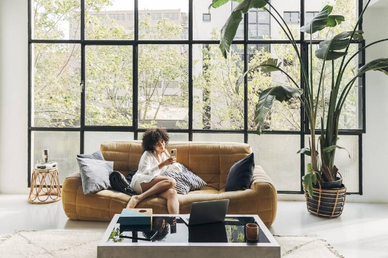 Woman sitting on low, slouchy sofa on her phone. 