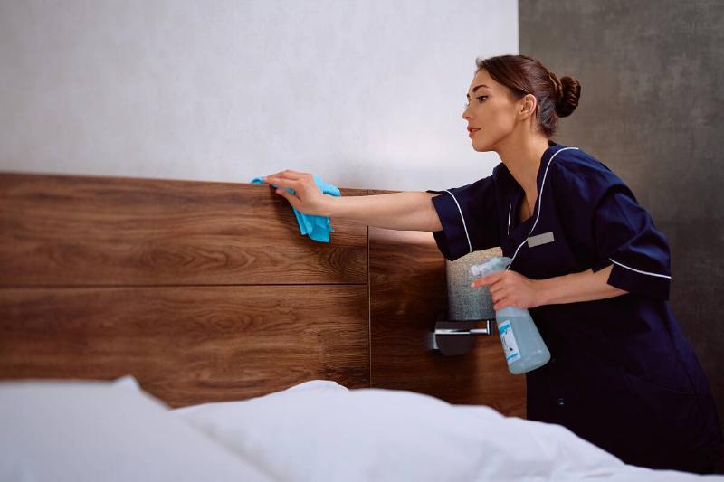 Woman cleaning headboard. 