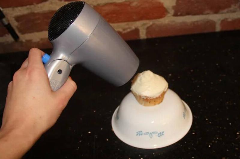 Hair dryer being used on a cupcake. 