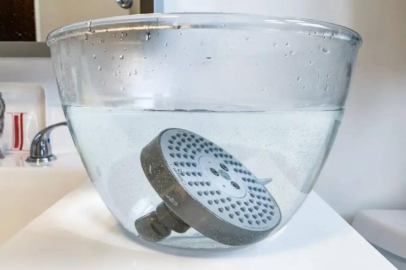 A shower head soaking in a bowl. 