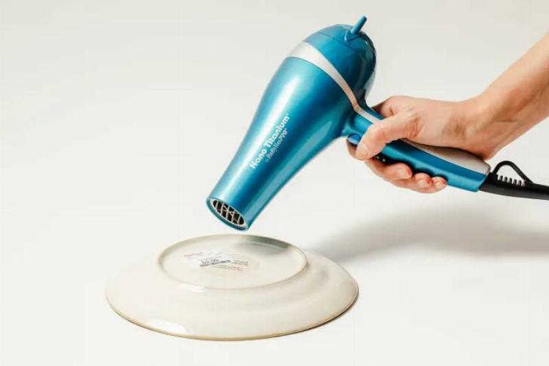 A hair dryer used on a sticker on the bottom of a plate. 