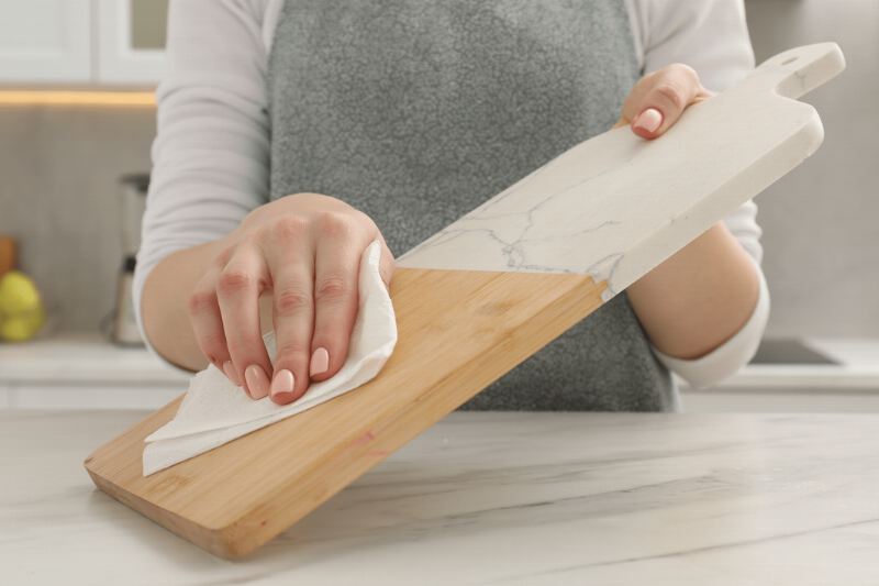 A person wiping off a cutting board. 