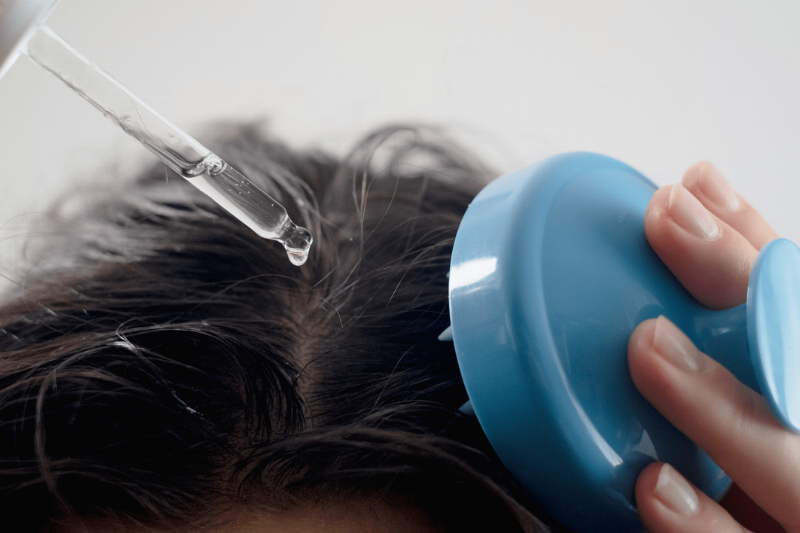 A man putting oil on his scalp.