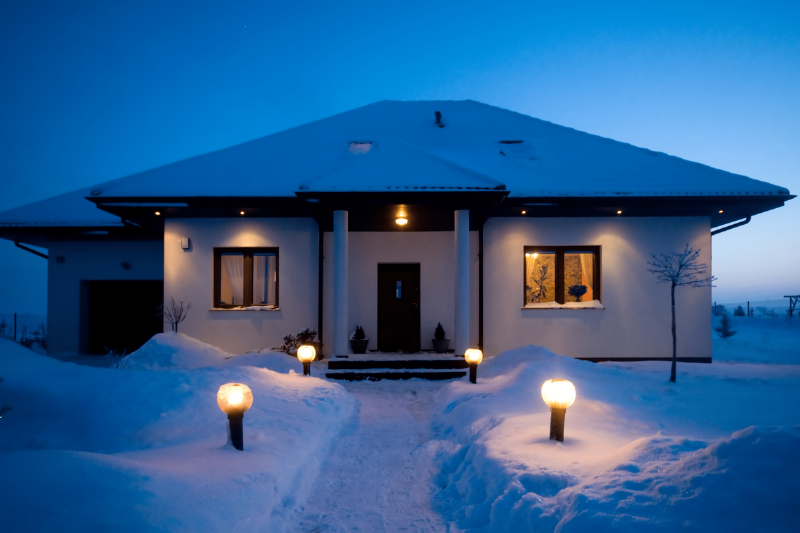 Lights lining the walkway to a house in snow. 