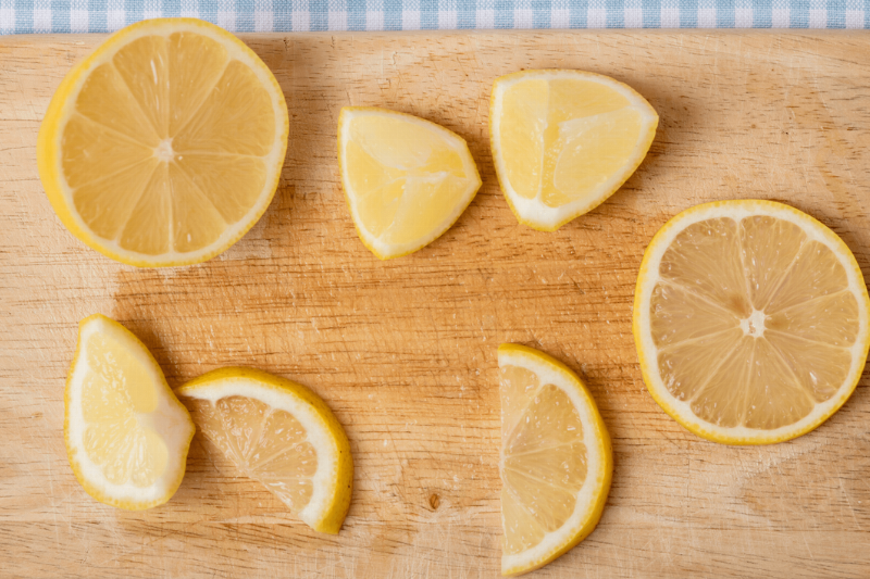 Lemon wedges on a wooden cutting board. 