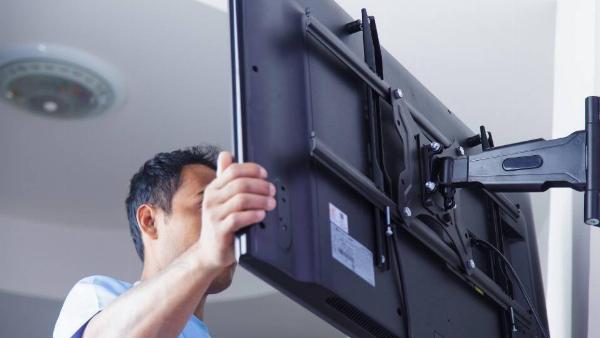 A man mounting a TV on a wall. 